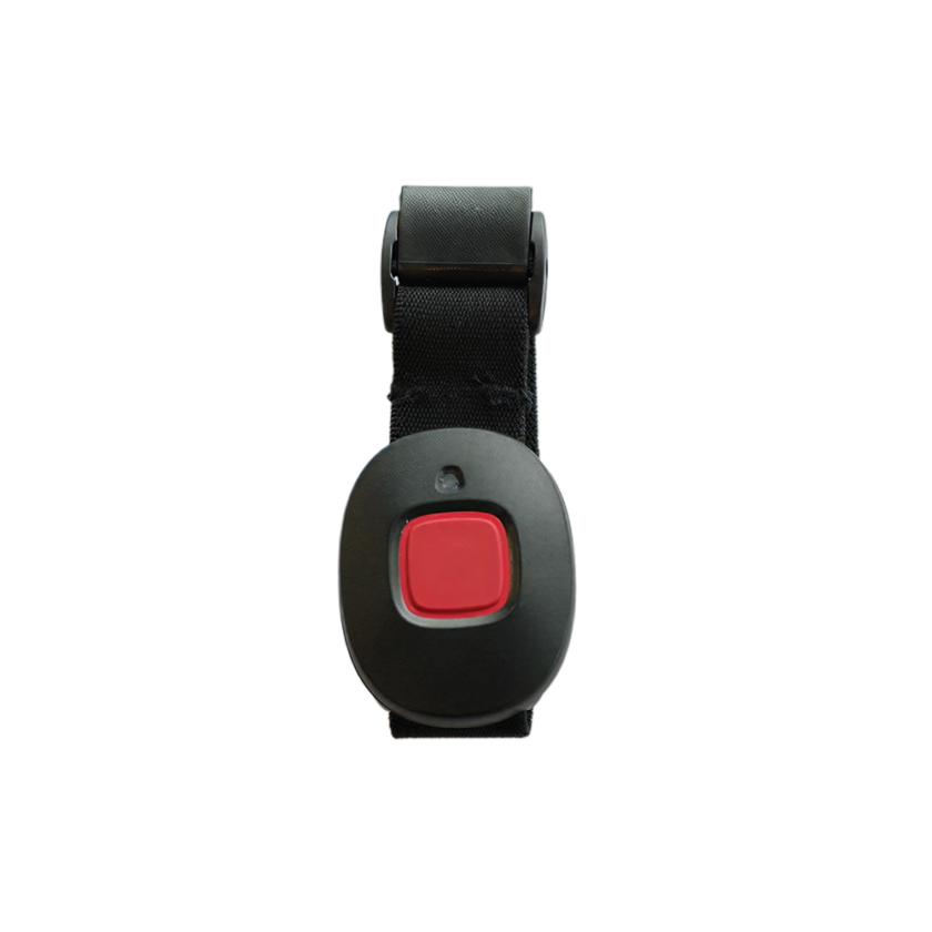 Svart nödlarm med röd knapp på svart tygarmband, fotograferat framifrån med vit bakgrund.