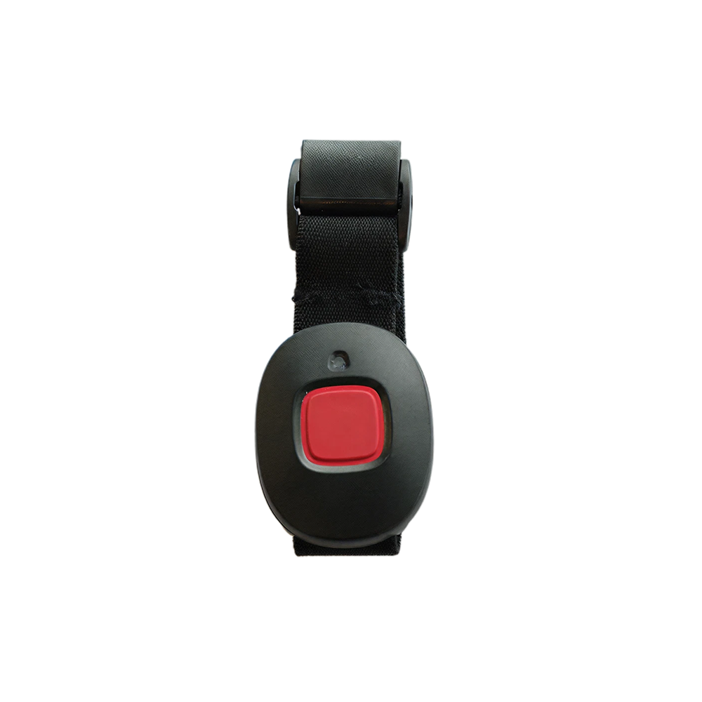 Svart nödlarm med röd knapp på svart tygarmband, fotograferat framifrån med vit bakgrund.